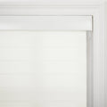 A white roller zebra Blind featuring alternating sheer and opaque horizontal stripes and a white valance, mounted within a decorative white window frame with a visible pull cord