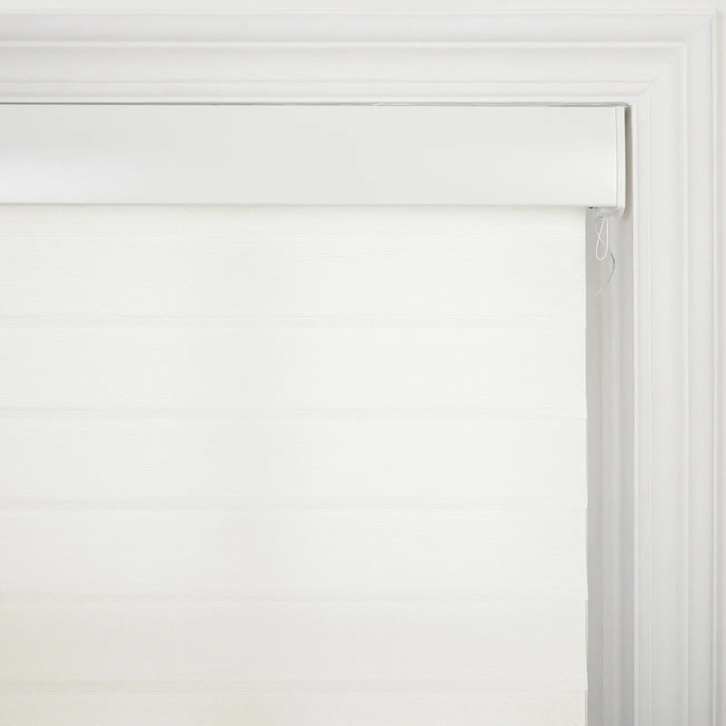A white roller zebra Blind featuring alternating sheer and opaque horizontal stripes and a white valance, mounted within a decorative white window frame with a visible pull cord