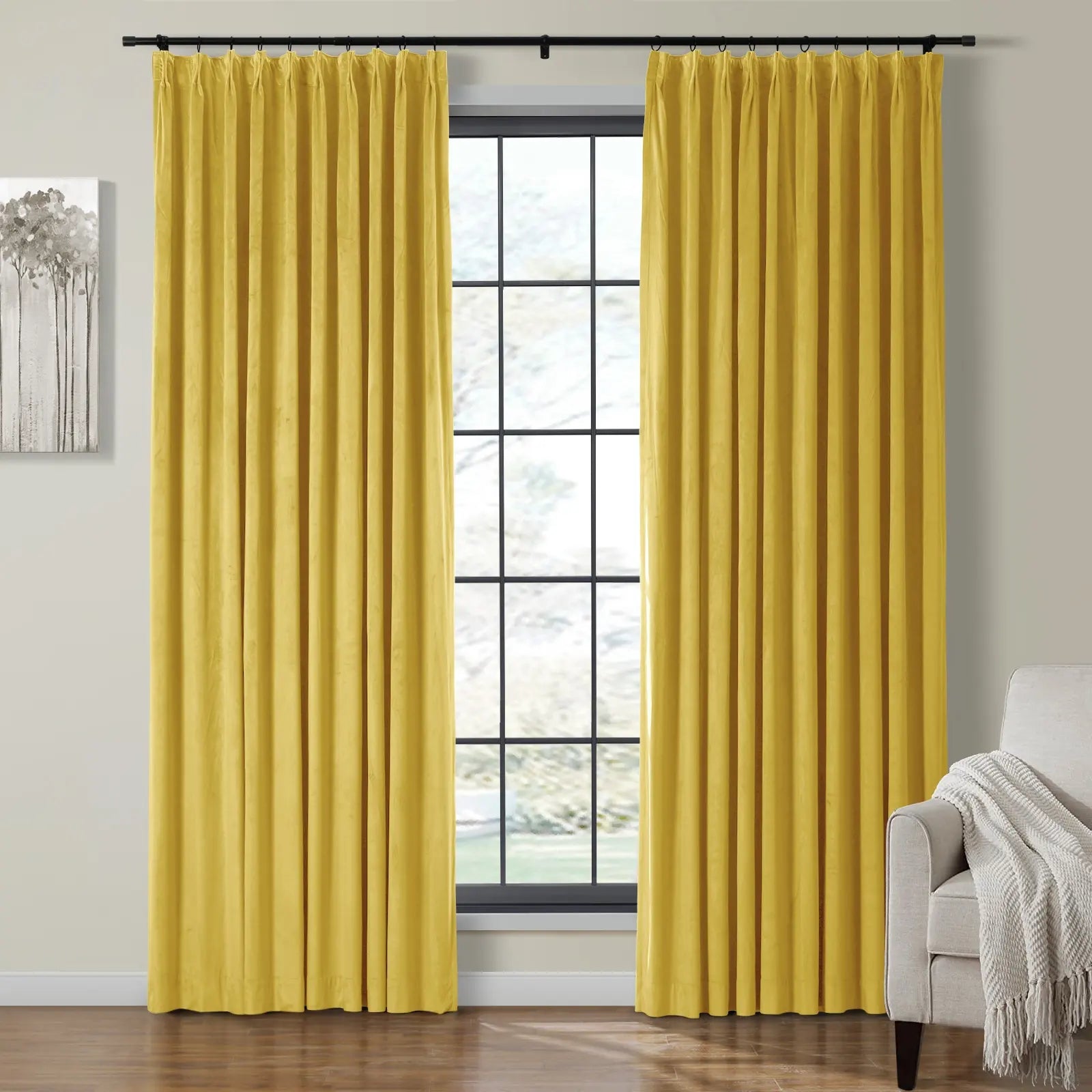 Bright yellow velvet pinch-pleated curtains frame a window with black grids in a modern living room featuring monochromatic tree art and a beige armchair with a textured white throw